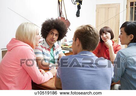 Group of young adult friends sitting around kitchen table View Large Photo Image Stock Photograph - Group of young adult friends sitting around kitchen table. Fotosearch