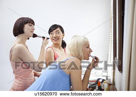 Group of young female friends applying make up View Large Photo Image Stock Image - Group of young female friends applying make up. Fotosearch