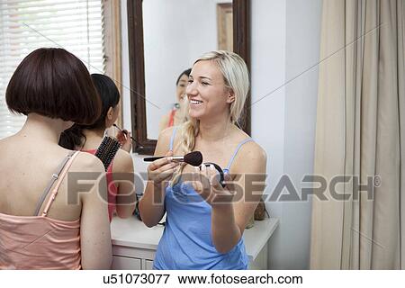 Group of young female friends putting on make up View Large Photo Image Stock Photo - Group of young female friends putting on make up. Fotosearch