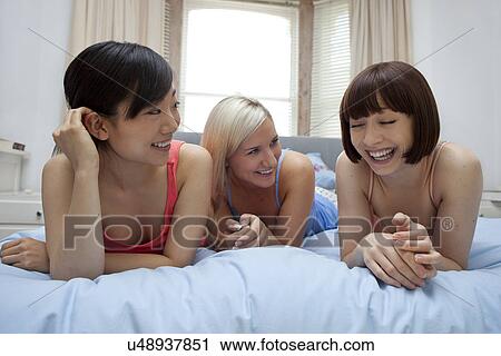 Group of young females on bed laughing View Large Photo Image Stock Image - Group of young females on bed laughing. Fotosearch