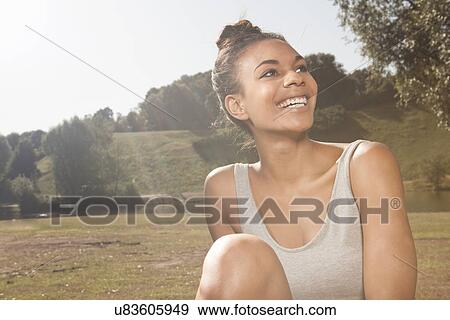 Stock Photo - Happy young woman in sunlight in a park. Fotosearch