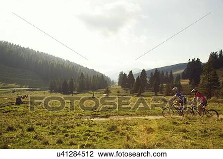 Stock Image - Man and woman mountain biking, Styria, Austria. Fotosearch