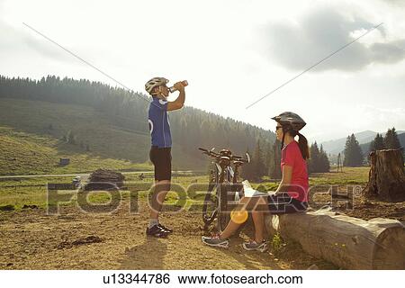 Stock Photograph - Man and woman resting with mountain bikes, Styria, Austria. Fotosearch