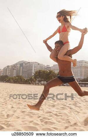Man carrying woman on shoulders running on Copacabana Beach, Rio de Janeiro, Brazil View Large Photo Image Stock Photo - Man carrying woman on shoulders running on Copacabana Beach, Rio de Janeiro, Brazil. Fotosearch