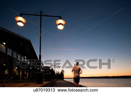 Stock Image - Man jogging on waterfront, Lulea, Sweden. Fotosearch