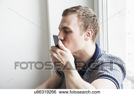 Stock Photograph - Man kissing mobile phone. Fotosearch
