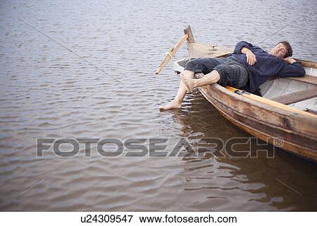 Man lying in rowing boat, Wales, UK View Large Photo Image Stock Photo - Man lying in rowing boat, Wales, UK. Fotosearch