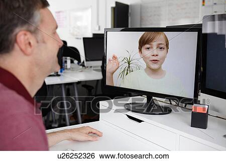 Man sitting at desk having video call with son View Large Photo Image Stock Photograph - Man sitting at desk having video call with son. Fotosearch