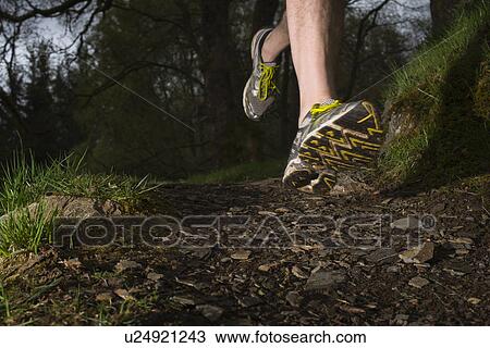 Stock Image - Man wearing trainers running, close up. Fotosearch