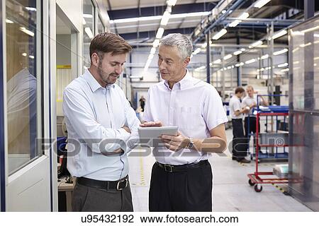 Manager and worker looking at digital tablet in engineering factory View Large Photo Image Stock Image - Manager and worker looking at digital tablet in engineering factory. Fotosearch