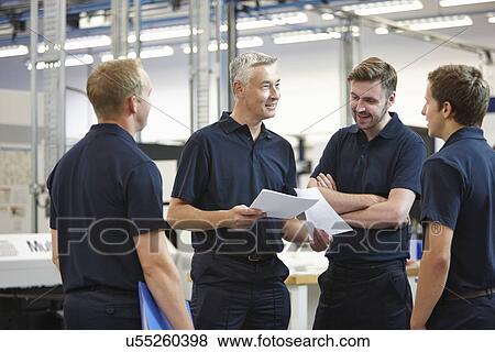 Stock Photo - Manager and workers discussing paperwork in engineering factory. Fotosearch