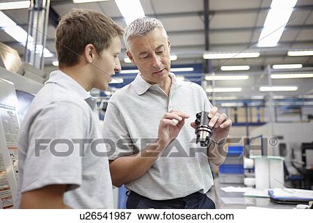 Manager and working looking at component in engineering factory View Large Photo Image Stock Photo - Manager and working looking at component in engineering factory. Fotosearch