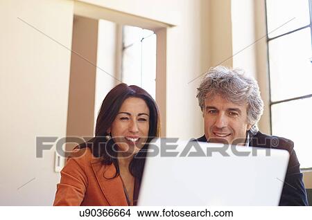 Picture - Mature businessman and woman using laptop. Fotosearch