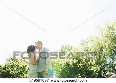 Stock Photo - Mature couple kissing in garden. Fotosearch