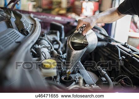 Mechanic pouring liquid into car View Large Photo Image Stock Photography - Mechanic pouring liquid into car. Fotosearch