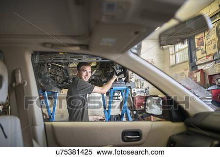 Stock Photography - Mechanic smiling toward camera through car window. Fotosearch