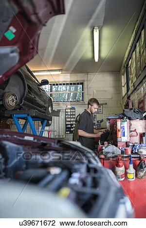 Stock Image - Mechanic working in garage. Fotosearch