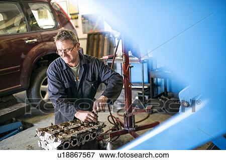 Mechanic working on car parts in garage View Large Photo Image Stock Photo - Mechanic working on car parts in garage. Fotosearch