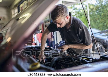 Mechanic working on car with bonnet open View Large Photo Image Stock Photo - Mechanic working on car with bonnet open. Fotosearch