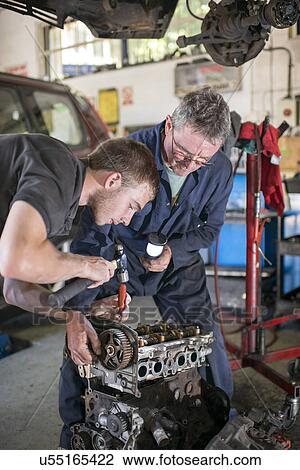 Stock Image - Mechanics working on car engine in garange. Fotosearch