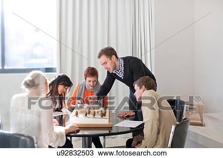 Stock Image - Meetings in architects office, looking at model. Fotosearch