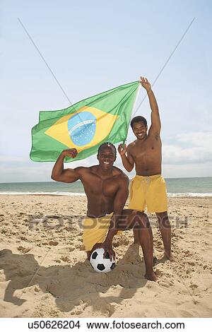 Picture - Men posing with brazilian flag on beach. Fotosearch