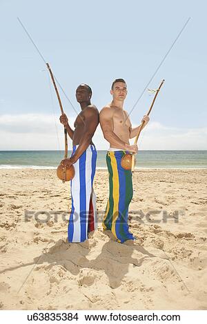 Picture - Men with berimbau on beach. Fotosearch