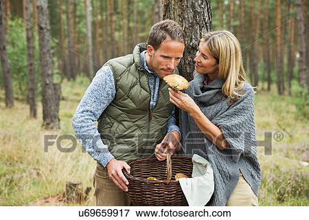 Stock Photo - Mid adult couple foraging for mushrooms in forest. Fotosearch