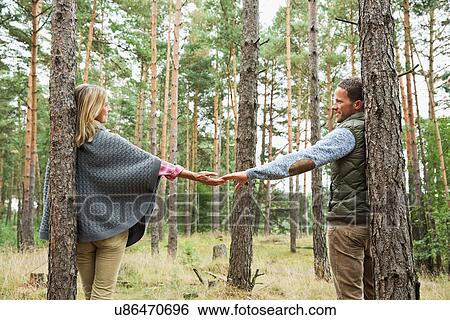 Stock Photograph - Mid adult couple holding hands in forest. Fotosearch