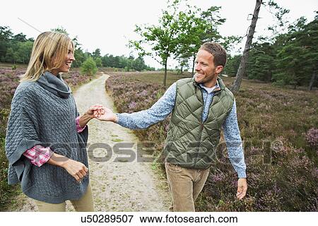Stock Photo - Mid adult couple holding hands on path. Fotosearch