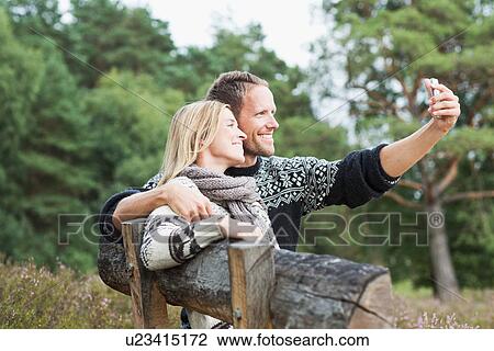 Mid adult couple on bench photographing themselves View Large Photo Image Stock Image - Mid adult couple on bench photographing themselves. Fotosearch