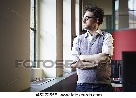 Stock Photography - Mid adult man looking out of window. Fotosearch