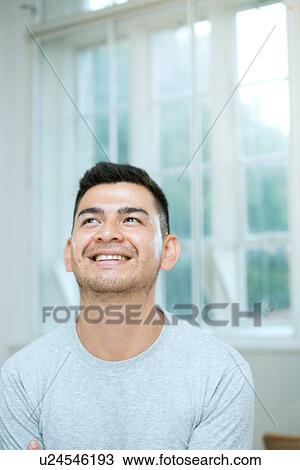 Stock Image - Mid adult man looking up. Fotosearch