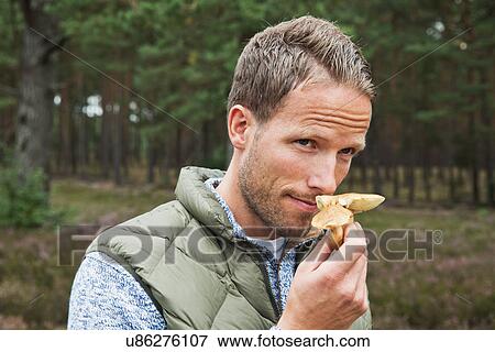 Stock Photo - Mid adult man smelling mushroom. Fotosearch
