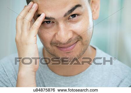 Stock Photograph - Mid adult man touching his face. Fotosearch