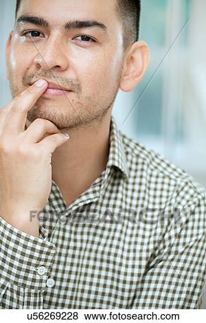 Stock Photo - Mid adult man touching his lip. Fotosearch