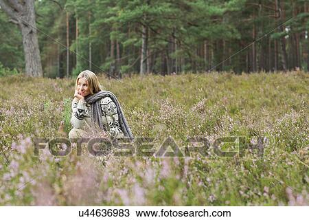 Mid adult woman in meadow with hand on chin View Large Photo Image Stock Image - Mid adult woman in meadow with hand on chin. Fotosearch
