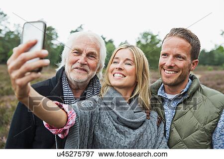 Stock Photo - Mid adult woman taking photograph with camera phone. Fotosearch