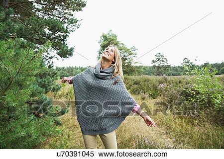 Mid adult woman wearing grey poncho looking up View Large Photo Image Stock Photography - Mid adult woman wearing grey poncho looking up. Fotosearch