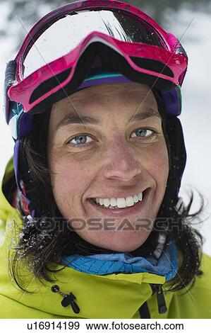 Stock Photo - Mid adult woman with ski goggles, smiling. Fotosearch
