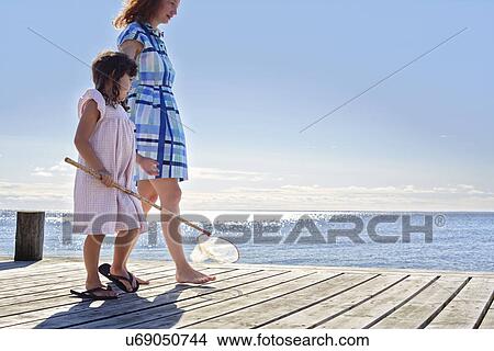 Picture - Mother and daughter on pier with fishing net, Utvalnas, Gavle, Sweden. Fotosearch