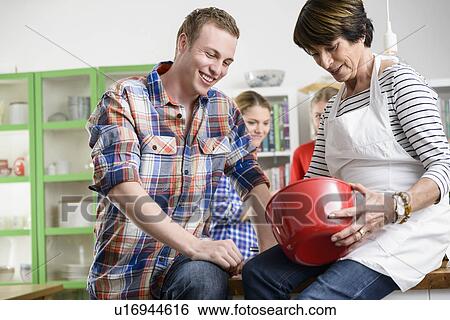 Stock Photograph - Mother and son looking into red bowl. Fotosearch