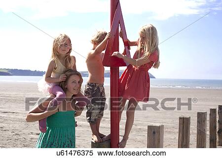 Stock Photography - Mother with three children on beach, Wales, UK. Fotosearch