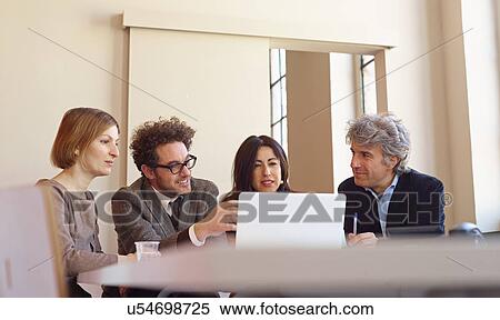 Office colleagues in meeting using laptop View Large Photo Image Stock Photography - Office colleagues in meeting using laptop. Fotosearch