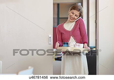 Stock Photograph - Office worker on cell phone, carrying tea tray. Fotosearch