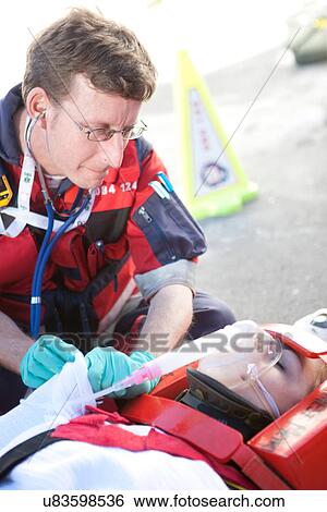 Paramedic using stethoscope, patient on stretcher wearing oxygen mask View Large Photo Image Stock Photograph - Paramedic using stethoscope, patient on stretcher wearing oxygen mask. Fotosearch