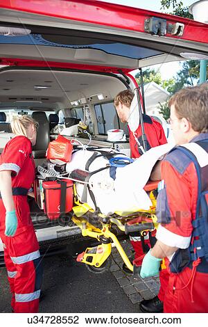 Paramedics lifting woman on stretcher into ambulance View Large Photo Image Stock Image - Paramedics lifting woman on stretcher into ambulance. Fotosearch