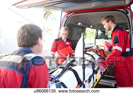Stock Photography - Paramedics lifting woman on stretcher into ambulance. Fotosearch