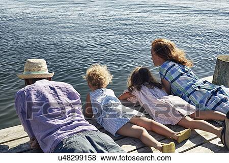 Stock Photo - Parents and daughters lying on pier, Utvalnas, Gavle, Sweden. Fotosearch