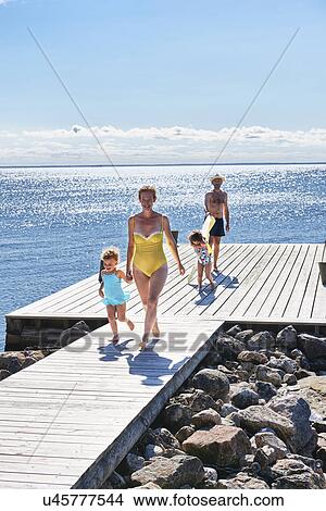 Picture - Parents and two young girls on pier, Utvalnas, Gavle, Sweden. Fotosearch